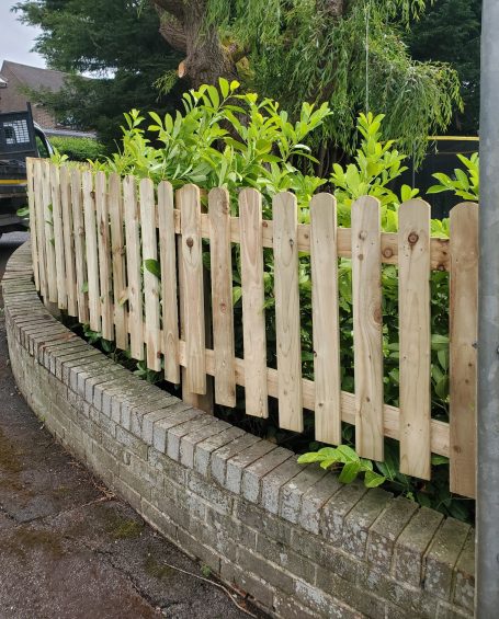 SRB Fencing @ South Normanton Wooden picket fence surrounding a curved garden with lush green plants.