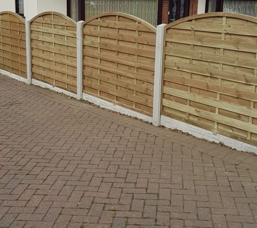Wooden garden fence panels with a brick pathway in front.