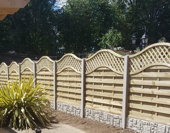 Wooden decorative fence with lattice detail and a small plant in the foreground.
