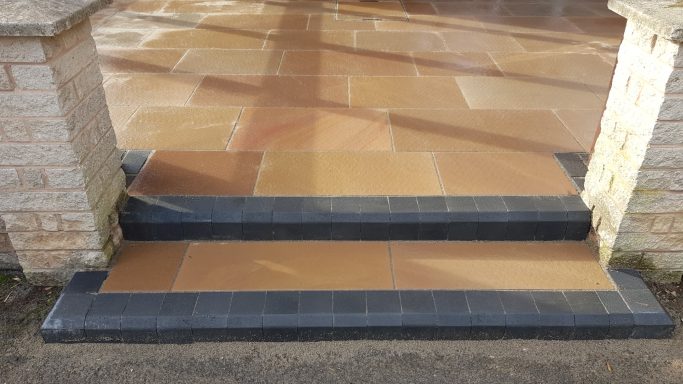 Paved entrance with beige stone steps and dark grey edging.