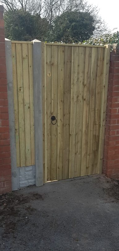 Wooden gate set in brick walls, leading to a pathway.