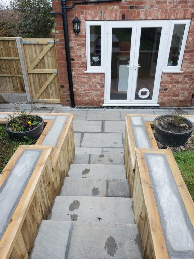 Stone steps lead down to a garden area with wooden planters on either side.