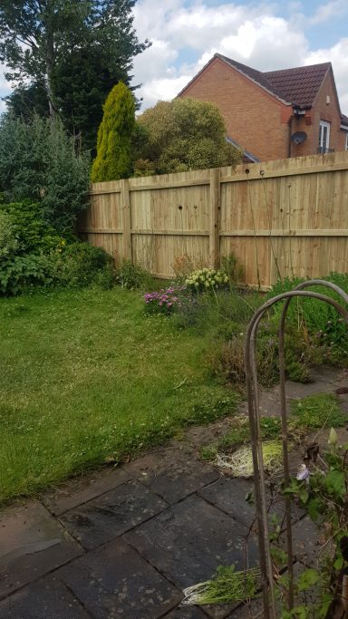 Gardening area with a fence, plants, and a patio in a residential setting.