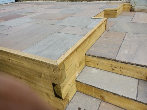 Wooden steps with a stone surface, leading up to a raised platform.