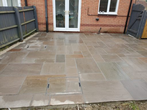 Paved outdoor area with patio stones and a wooden fence.