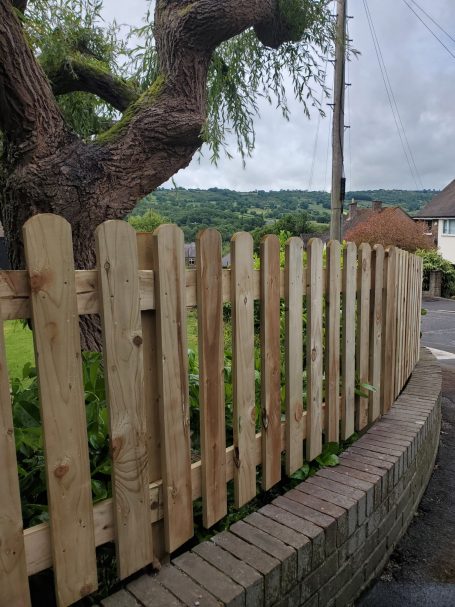 SRB Fencing @ South Normanton Wooden fence curving along a path, with greenery and hills in the background.