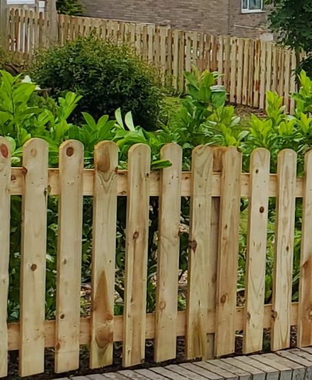 SRB Fencing @ South Normanton Wooden fence with pointed tops, surrounded by greenery in a residential area.