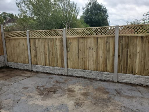 Wooden fence panels with lattice detailing, set against a cloudy sky.